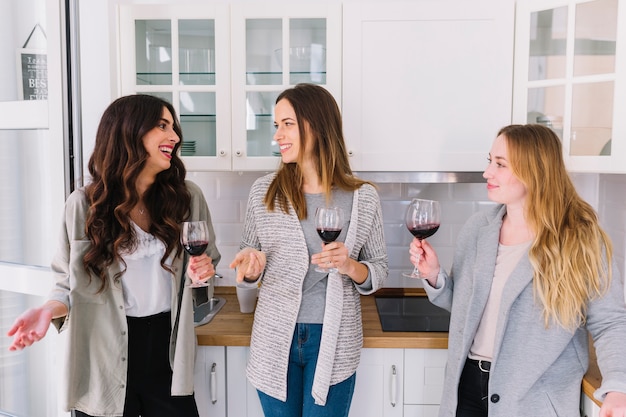 Free photo friends drinking wine and speaking in kitchen