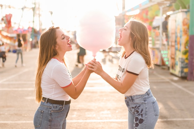 Friends eating cotton candy in the amusement park