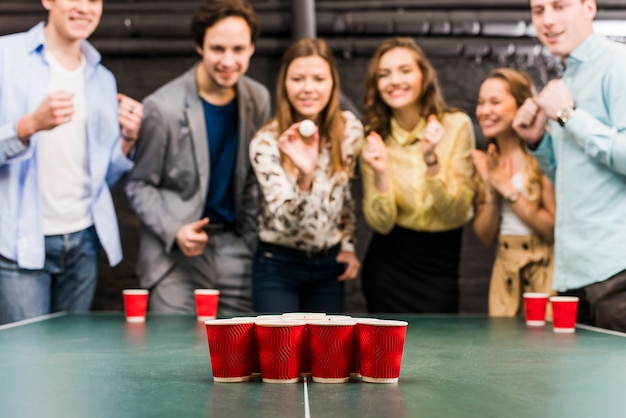 Free photo friends enjoying beer pong game on table in bar