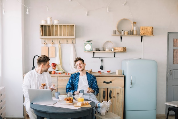 Free photo friends enjoying breakfast sitting in front of table in kitchen