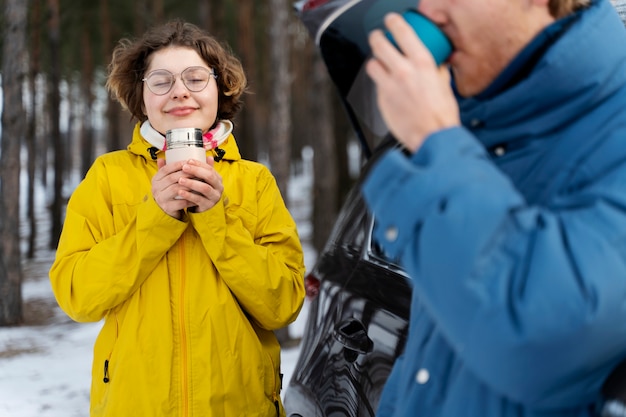 Friends enjoying hot drink while on winter trip