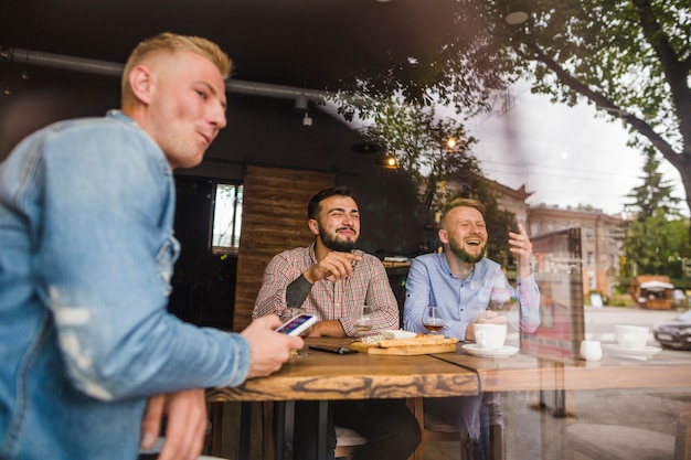 Free Photo friends enjoying in the restaurant seen from window glass