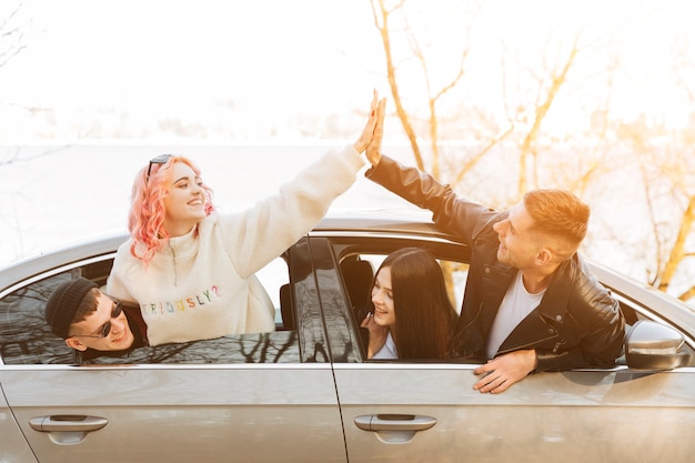 Friends giving high five from car window 