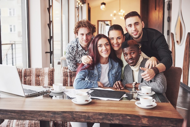 Friends having fun at restaurant. Three boys and two girls making selfie and laughing.