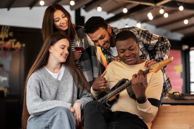 Friends having a good time while listening to their friend playing guitar