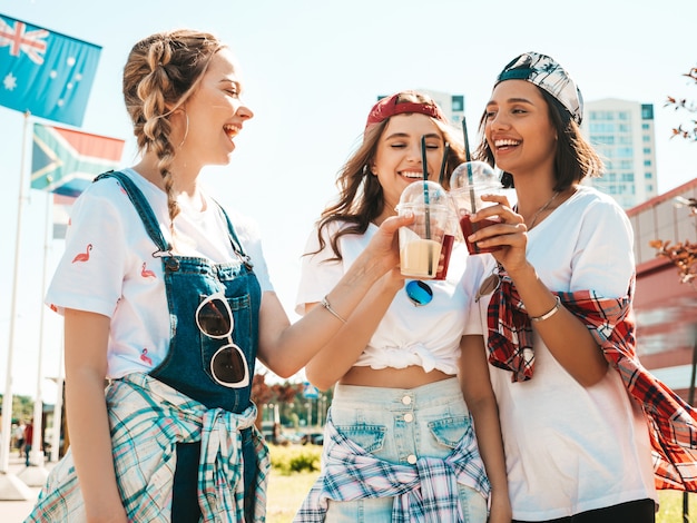 Friends holding and drinking fresh cocktail smoothie drink in plastic cup with straw