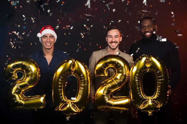 Free photo friends holding golden balloons for new years