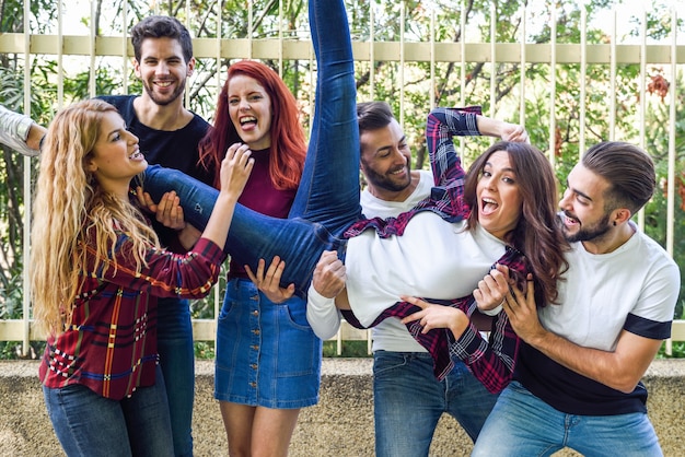 Free photo friends lifting a girl in the air leaning on everyone