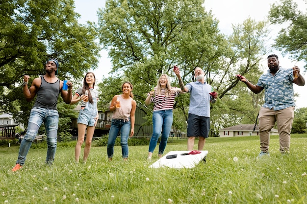 Free photo friends playing cornhole at a summer party in the park