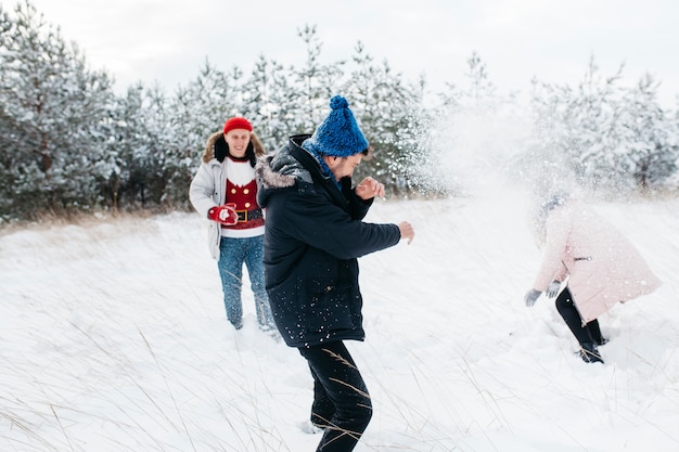 Friends playing snowballs in winter forest 