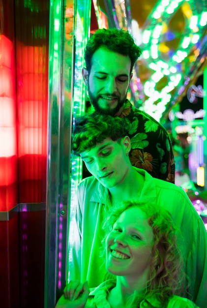 Free Photo friends posing in green light at funfair