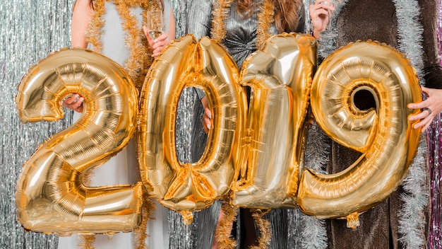 Free photo friends posing with golden balloons at a new year party