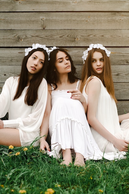 Free photo friends sitting in the grass with flower diadem