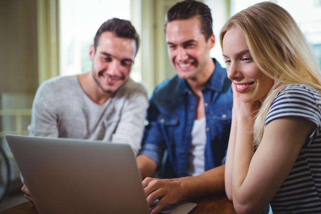 Friends sitting at table and using laptop in cafÃ©