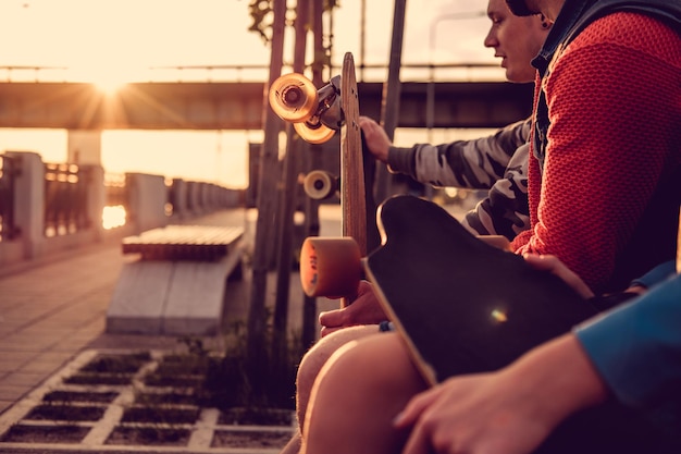 Free photo friends, skateboard riders relaxing on a bench after riding at sunset.