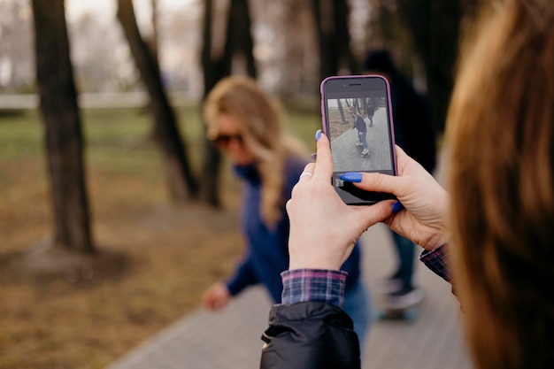 Free photo friends skateboarding in the park while woman takes pictures