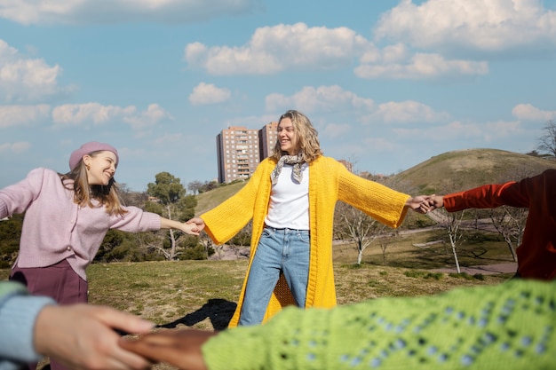 Free Photo friends spinning and holding hands in an outdoor field