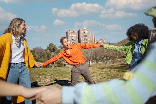 Free photo friends spinning and holding hands in an outdoor field