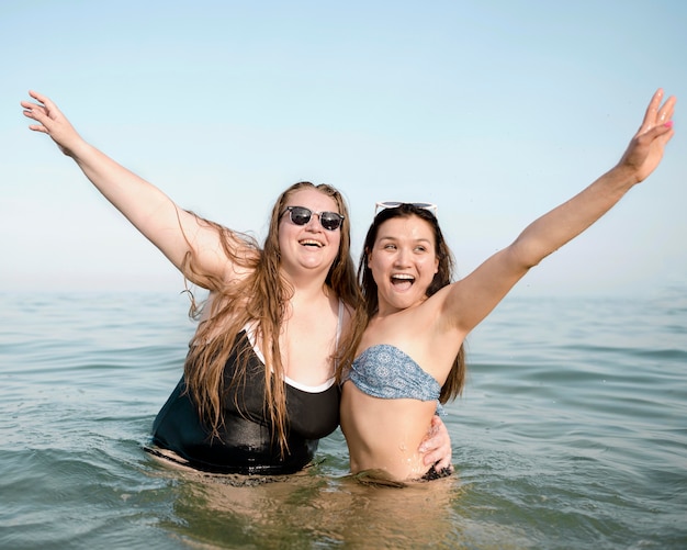 Free Photo friends standing in the water with hands in the air