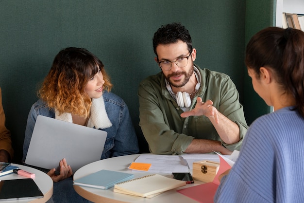 Friends studying from notebook and laptop during study session