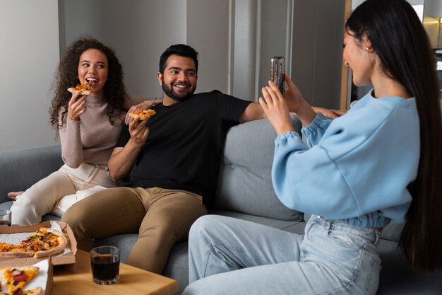 Friends taking pictures while eating pizza at home