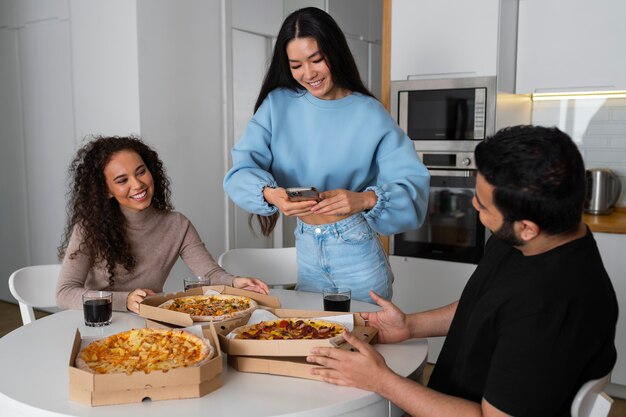 Friends taking pictures while eating pizza at home