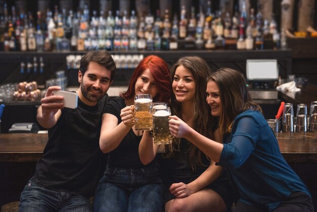 Friends taking a selfie at bar counter using mobile phone