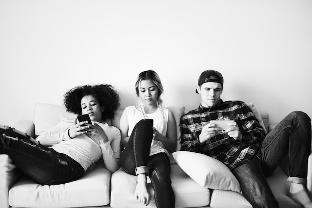 Free photo friends using mobile phones on the couch