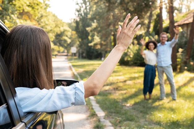 Free photo friends waving at each other outdoors from the car