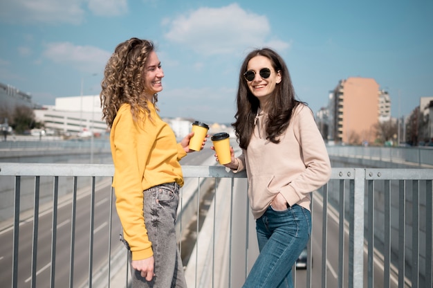 Free photo friends wearing sunglasses holding cup of coffee