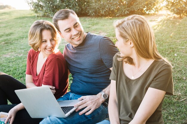 Friends with laptop sitting on ground