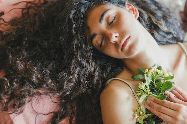 From above brunette sleeping with flowers