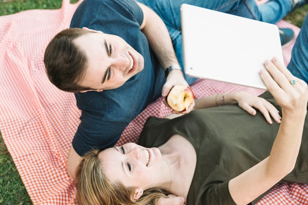 Free photo from above couple using tablet on picnic