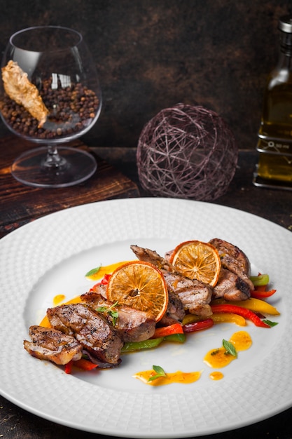 Free Photo from above fried meat with fried vegetables and orange and brandy glass in white plate