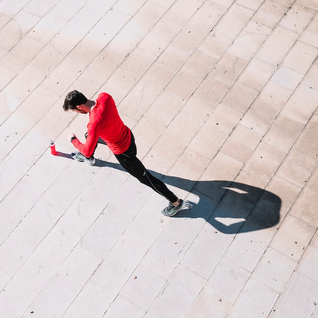 From above man doing lunges on pavement