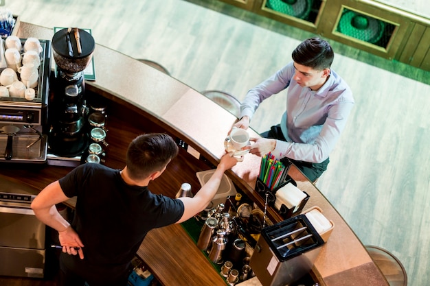 From above man giving drink to customer