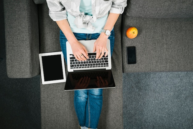 Free photo from above woman browsing laptop on sofa