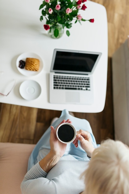 Free photo from above woman drinking coffee near laptop