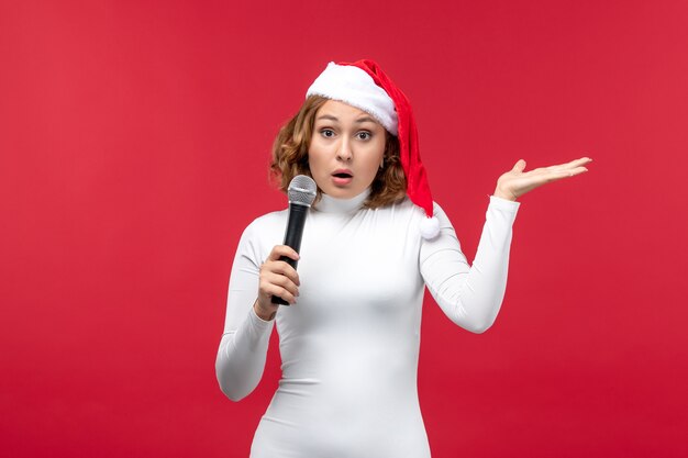 Fron view of young female holding mic on red