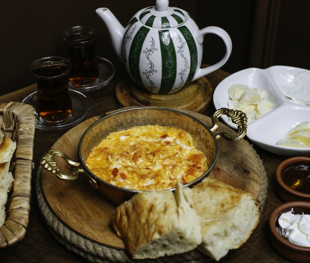 A front close up view breakfast table with cooked eggs and with hot tea on the brown floor