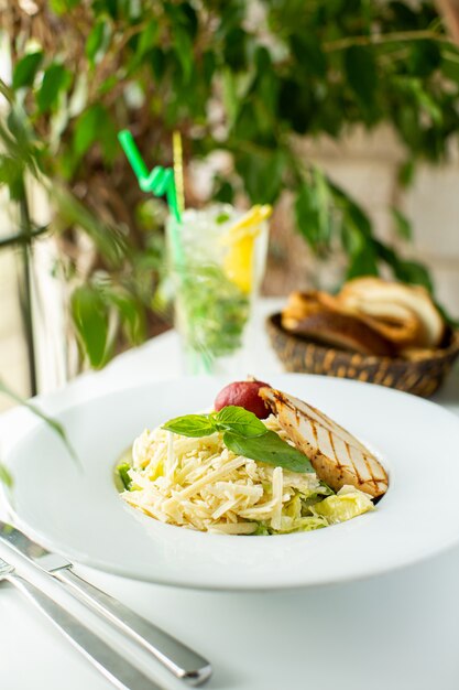 A front close up view tasty meal cooked pasta with green leaf and meat inside white plate on the white desk