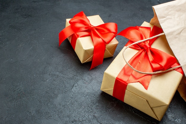 Front close view of beautiful gifts with red ribbon on a dark table