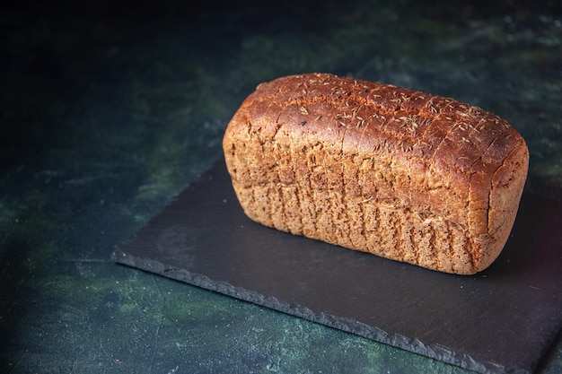 Front close view of black bread on black board on mixed colors distressed background