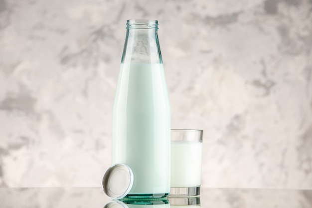 Free photo front close view of glass bottle filled with milk cup cap on white smoke background with free space