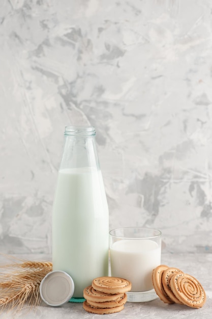 Front close view of glass cup bottle filled with milk cap and cookies spikes on stained white surface