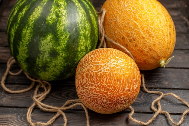 Free Photo front close view green watermelon whole round formed fresh and juicy fruit with melons on the brown rustic desk fruit juice fresh