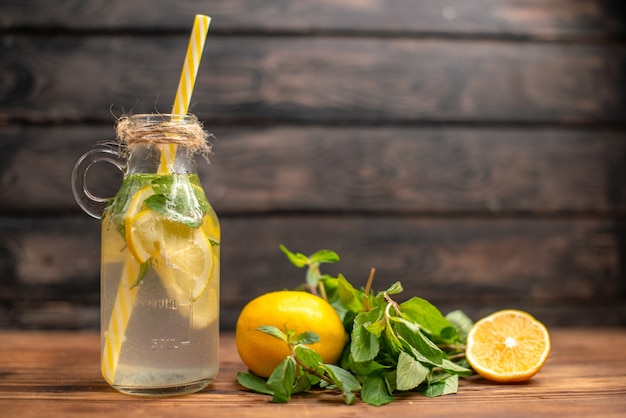 Front close view of natural fresh detox water served with tube mint and orange on a brown background