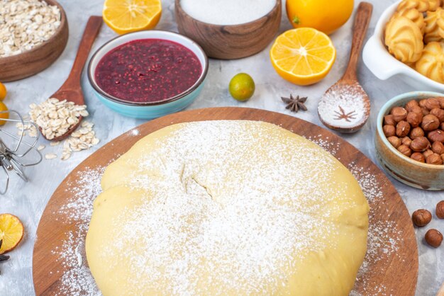 Front close view of raw pastry on round board and set of various foods grater on ice background