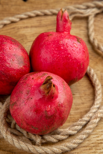 Front close view red pomegranates with ropes on wooden desk color fruit juice photo tree