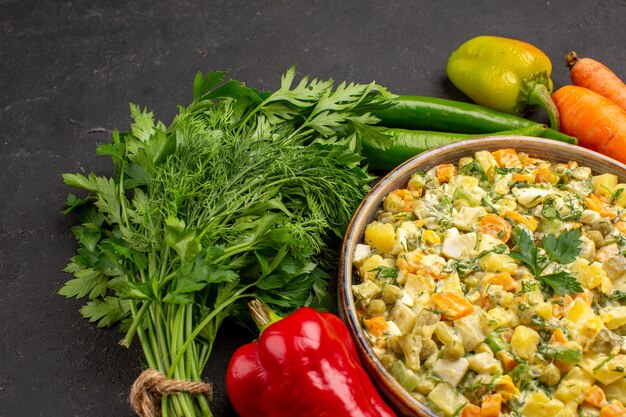 Front close view of tasty salad with greens and vegetables on dark surface